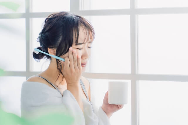 歯磨きの際に痛みを感じる女性