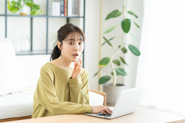 PCを見ながら驚く女性