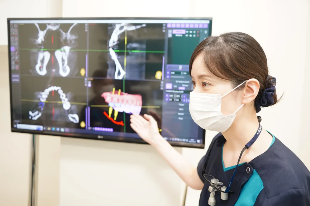 インプラント治療についてシミュレーション画面を見せながら説明を行う歯科医師