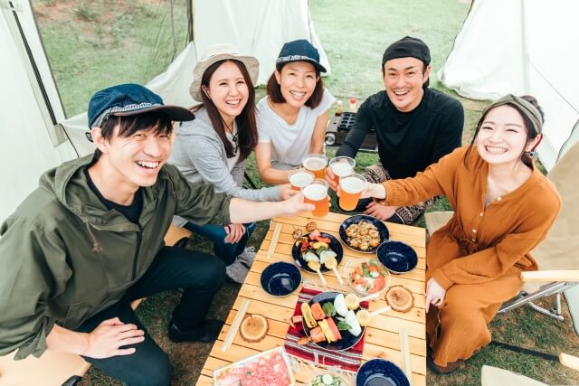 キャンプで乾杯をする５人の男女