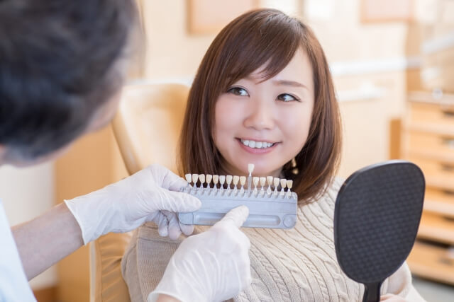 歯科医院で歯の色を確認する女性